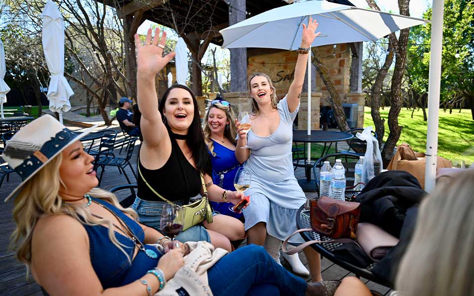 Bachelorette Party 24 Bridesmaids celebrating a bachelorette party on a Fredericksburg TX wine tour, enjoying wine and scenic vineyard views in Texas Hill Country